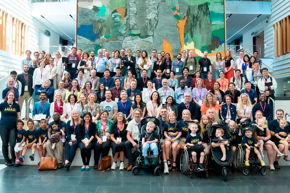 Group photo of about 100 collaborators with, in front, the children and their families wearing blue “I know a Hero” T-shirts, at the first Undiagnosed Hackathon in Stockholm 2023